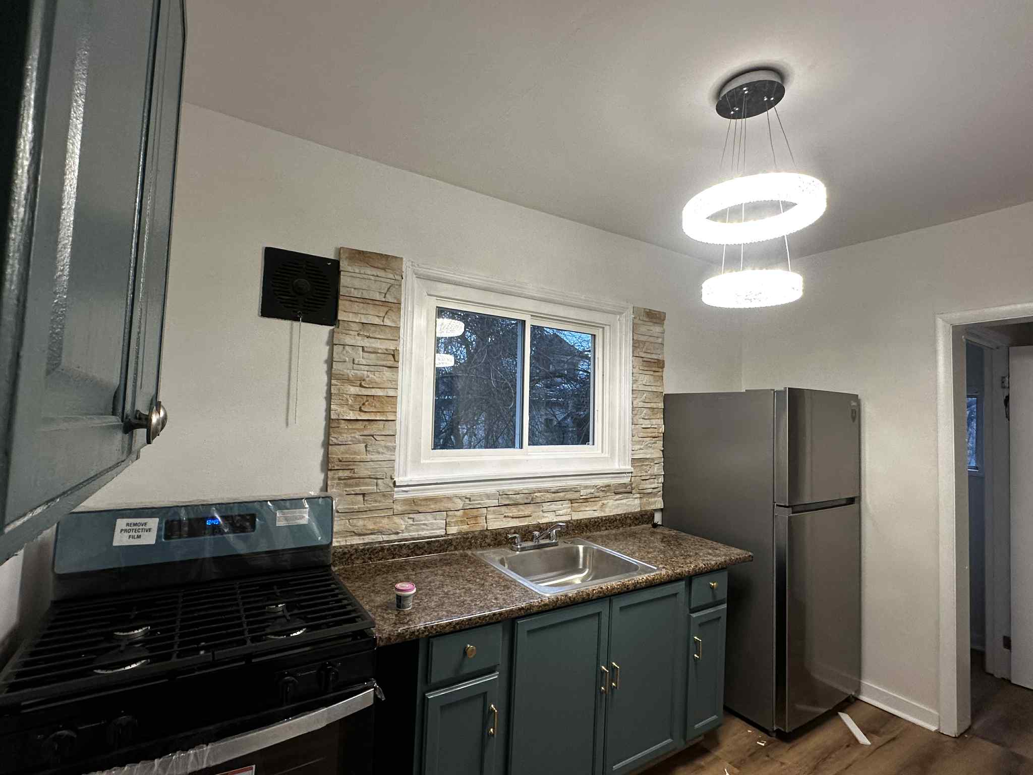 Kitchen with Stone Backsplash and Modern Lighting